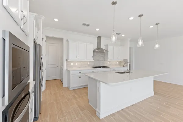 a kitchen with kitchen island a sink stainless steel appliances and wooden floor