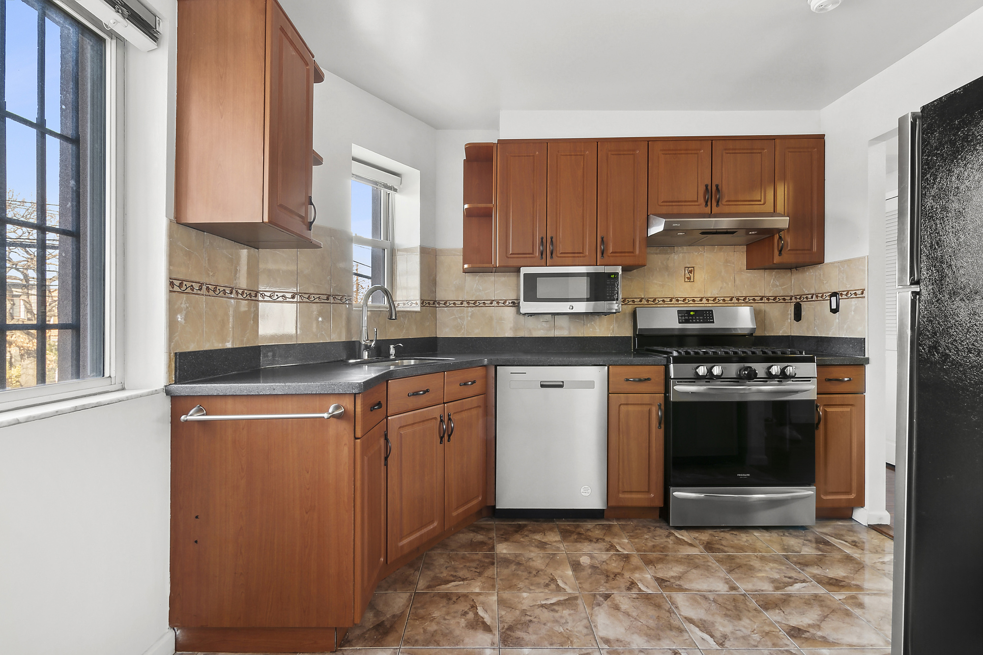 21-08 Butler Avenue, Unit J2 Queens, NY 11385 - Photo 5 of 14 a kitchen with stainless steel appliances granite countertop a stove a sink and a microwave