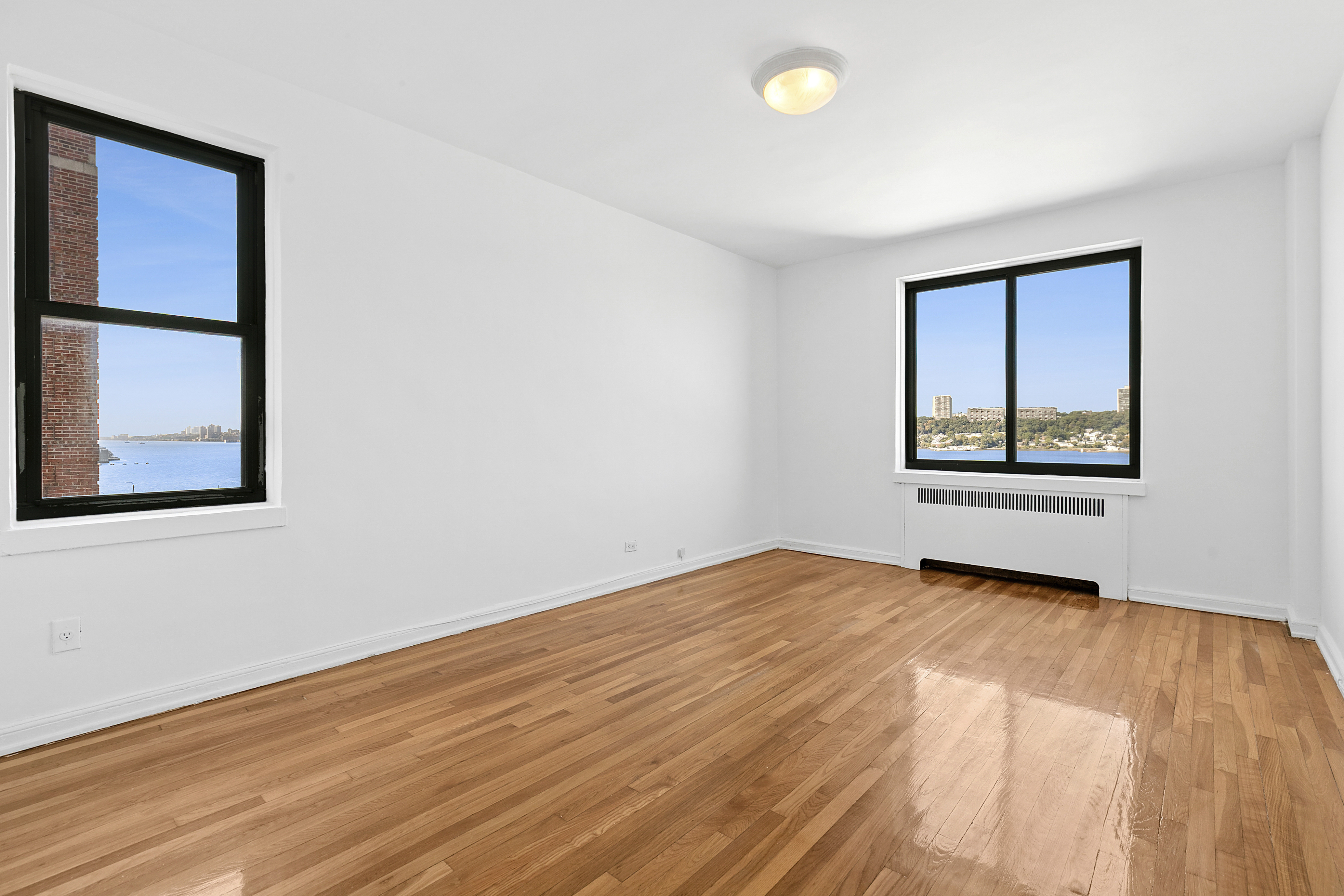 159-00 Riverside Drive West, Unit 4L70 Manhattan, NY 10032 - Photo 5 of 18 a view of an empty room with wooden floor and a window