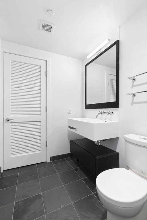 319 A Street, Unit 211 Boston, MA 02210 - Photo 13 of 24 a bathroom with a toilet a sink and mirror