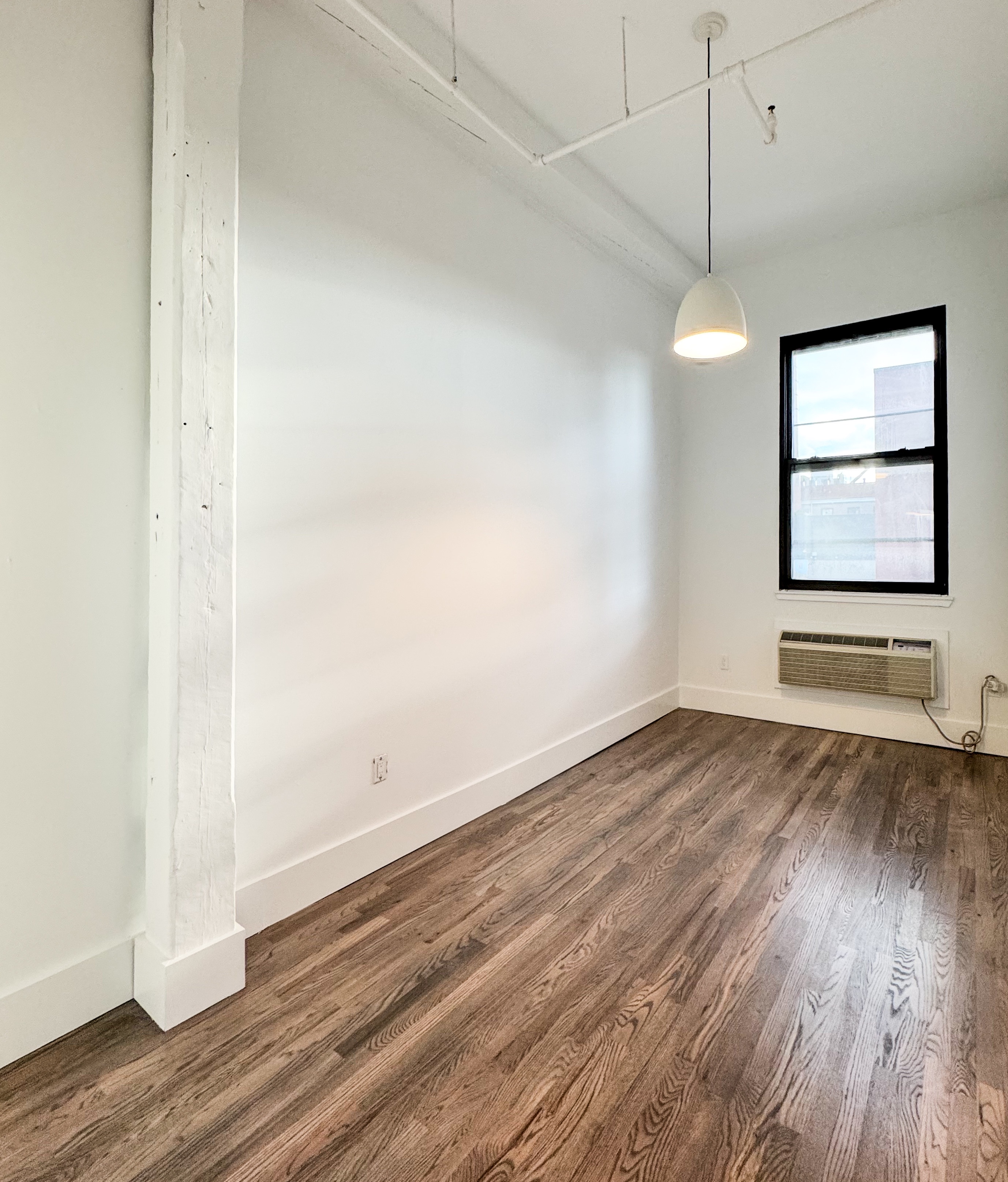 44 Berry Street, Unit 4J Brooklyn, NY 11249 - Photo 4 of 8 an empty room with wooden floor and windows