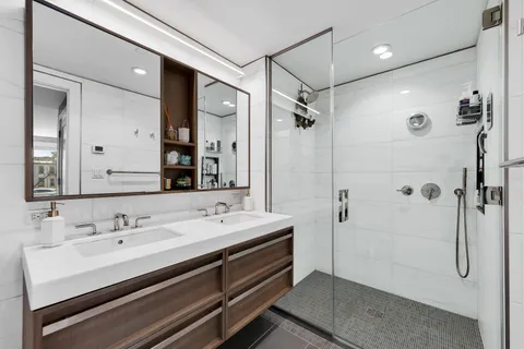 a bathroom with a double vanity sink mirror and shower