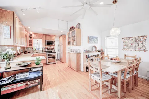 a kitchen with stainless steel appliances kitchen island granite countertop a table chairs in it and wooden floors