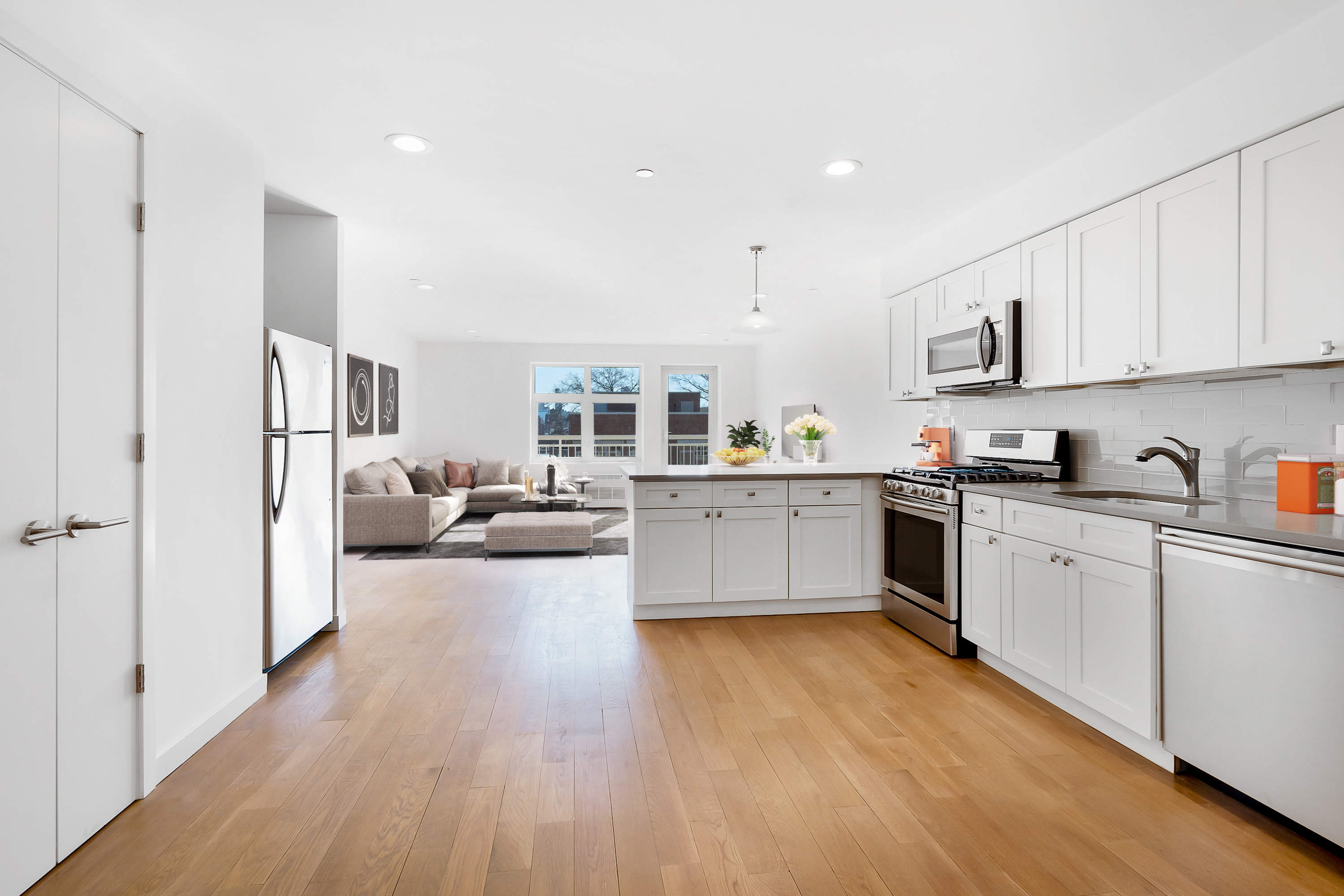 26-20 14th Place, Unit 3D Queens, NY 11102 - Photo 2 of 12 a large white kitchen with cabinets a sink a window and stainless steel appliances
