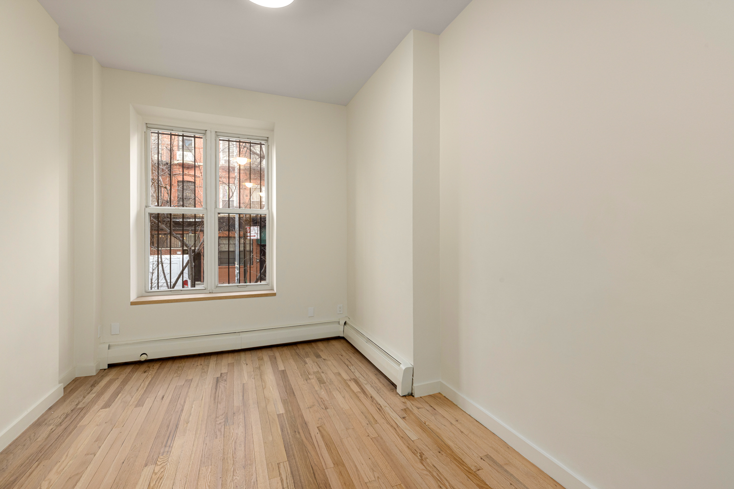 518 East 11th Street, Unit 1B Manhattan, NY 10009 - Photo 2 of 9 a view of an empty room with wooden floor and a window