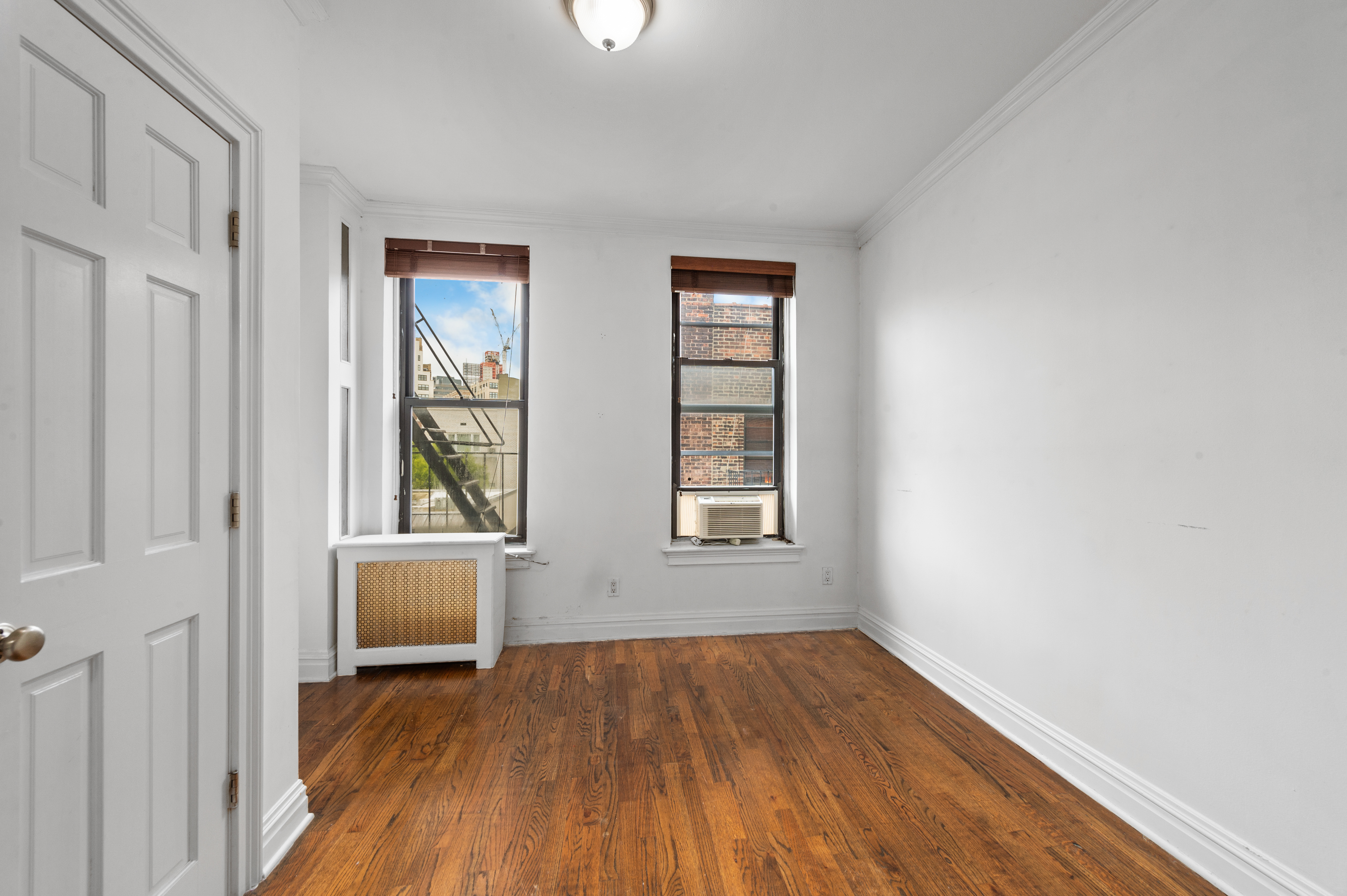 142 Sullivan Street, Unit 21 Manhattan, NY 10012 - Photo 5 of 8 an empty room with wooden floor and windows