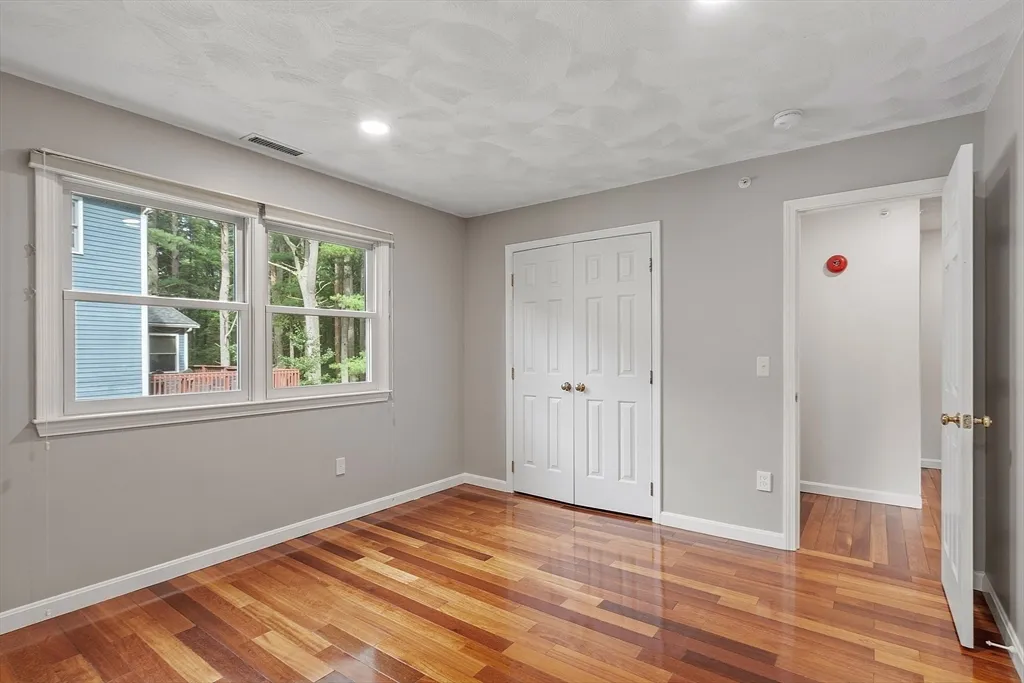 a view of an empty room with wooden floor and windows