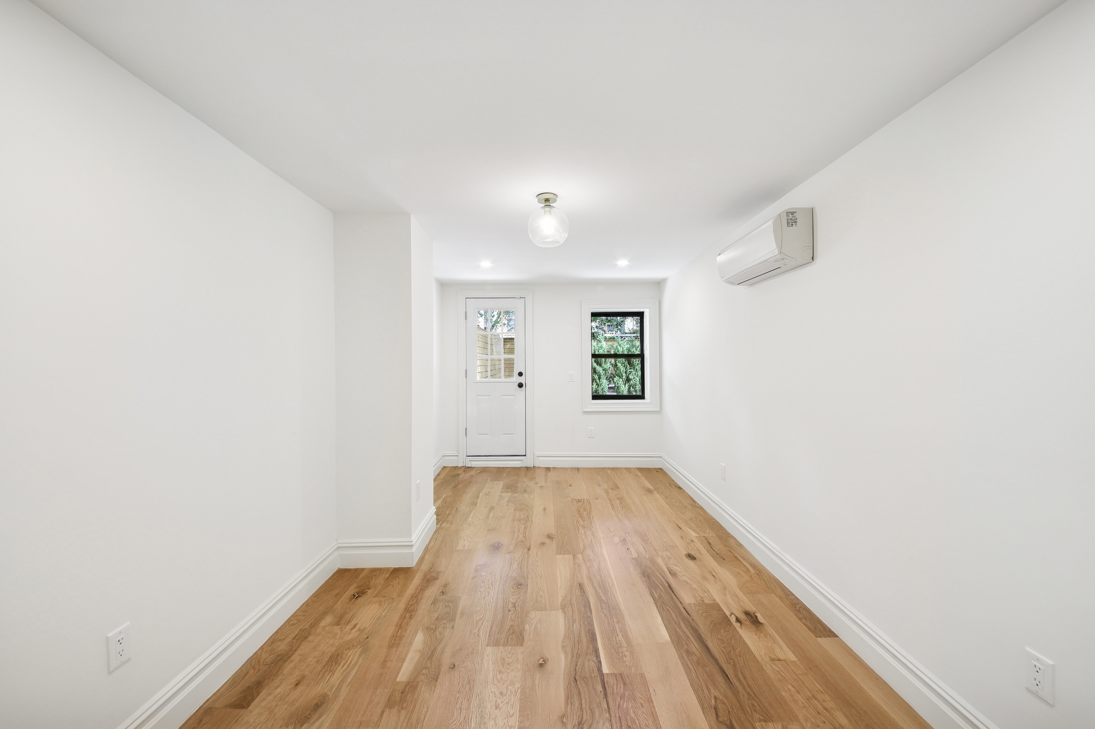 239 Madison Street, Unit 1 Brooklyn, NY 11216 - Photo 7 of 14 a view of an empty room with wooden floor and a window