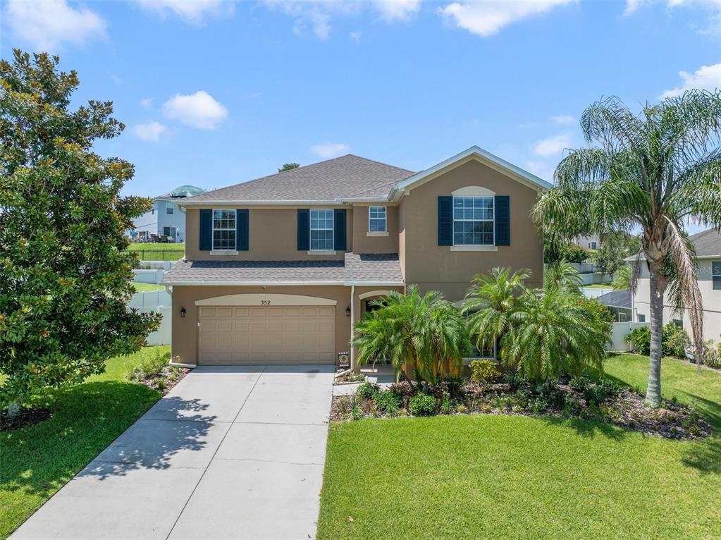 a front view of a house with a yard and trees