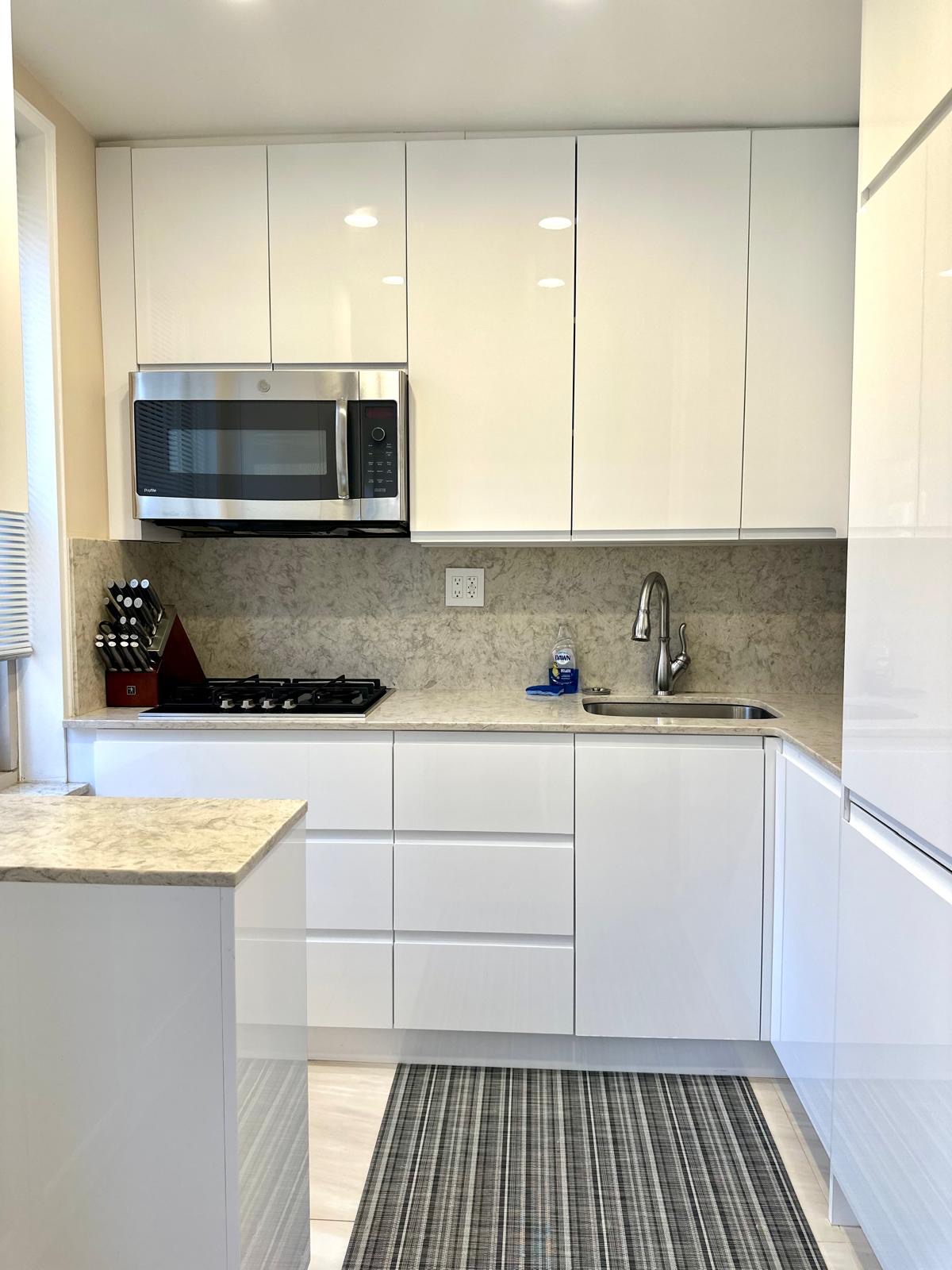 309 East 87th Street, Unit 3L Manhattan, NY 10128 - Photo 3 of 14 a kitchen with granite countertop white cabinets and stainless steel appliances