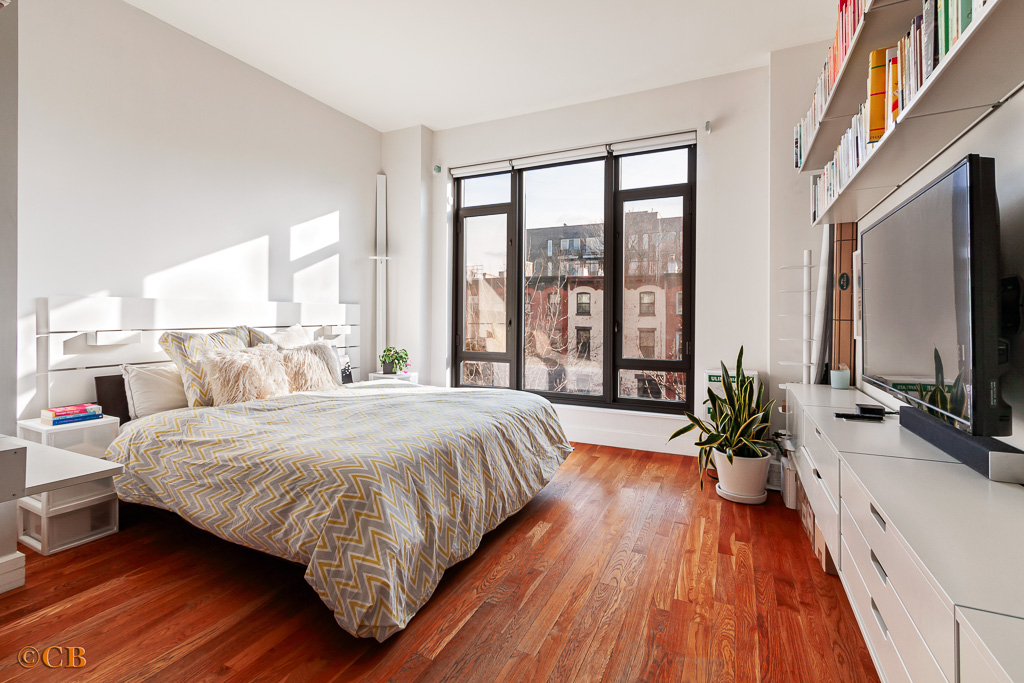 315 Gates Avenue, Unit 3H Brooklyn, NY 11216 - Photo 2 of 12 a bedroom with a large bed and a flat tv screen on a dresser