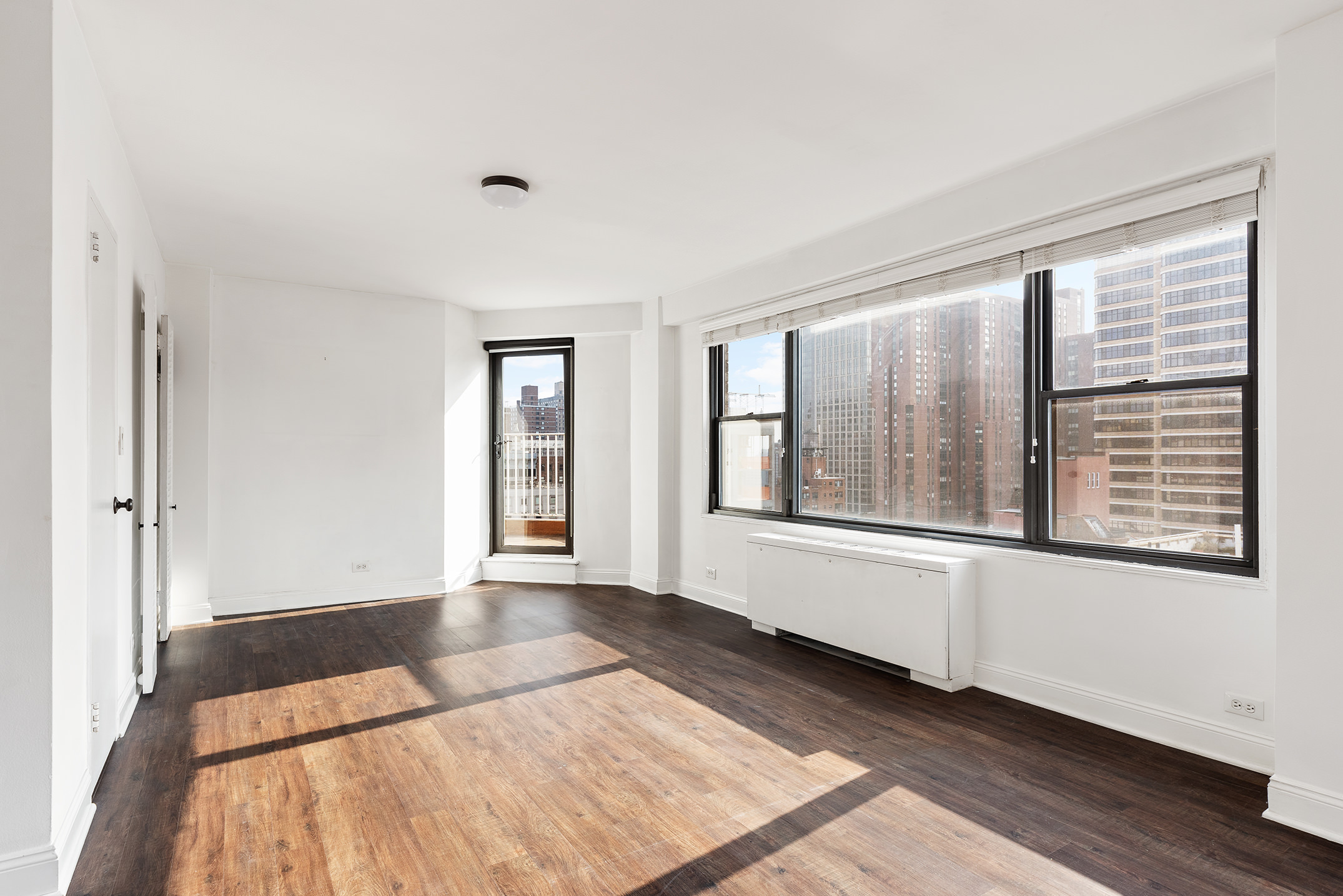 120 East 90th Street, Unit 16E Manhattan, NY 10128 - Photo 4 of 15 a view of an empty room with wooden floor and a window
