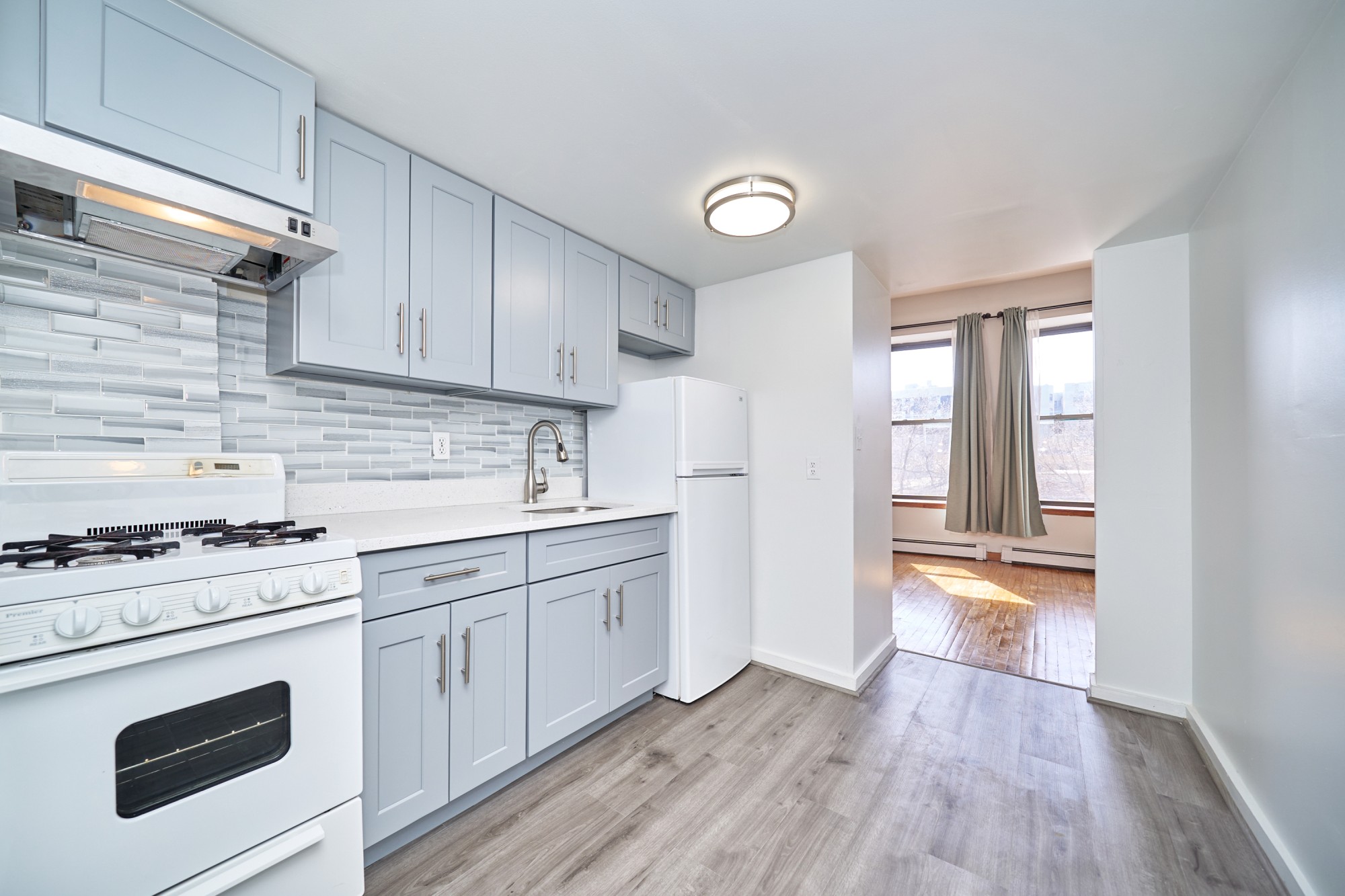 357 West 120th Street, Unit 2F Manhattan, NY 10027 - Photo 6 of 8 a kitchen with granite countertop wooden floors and white stainless steel appliances