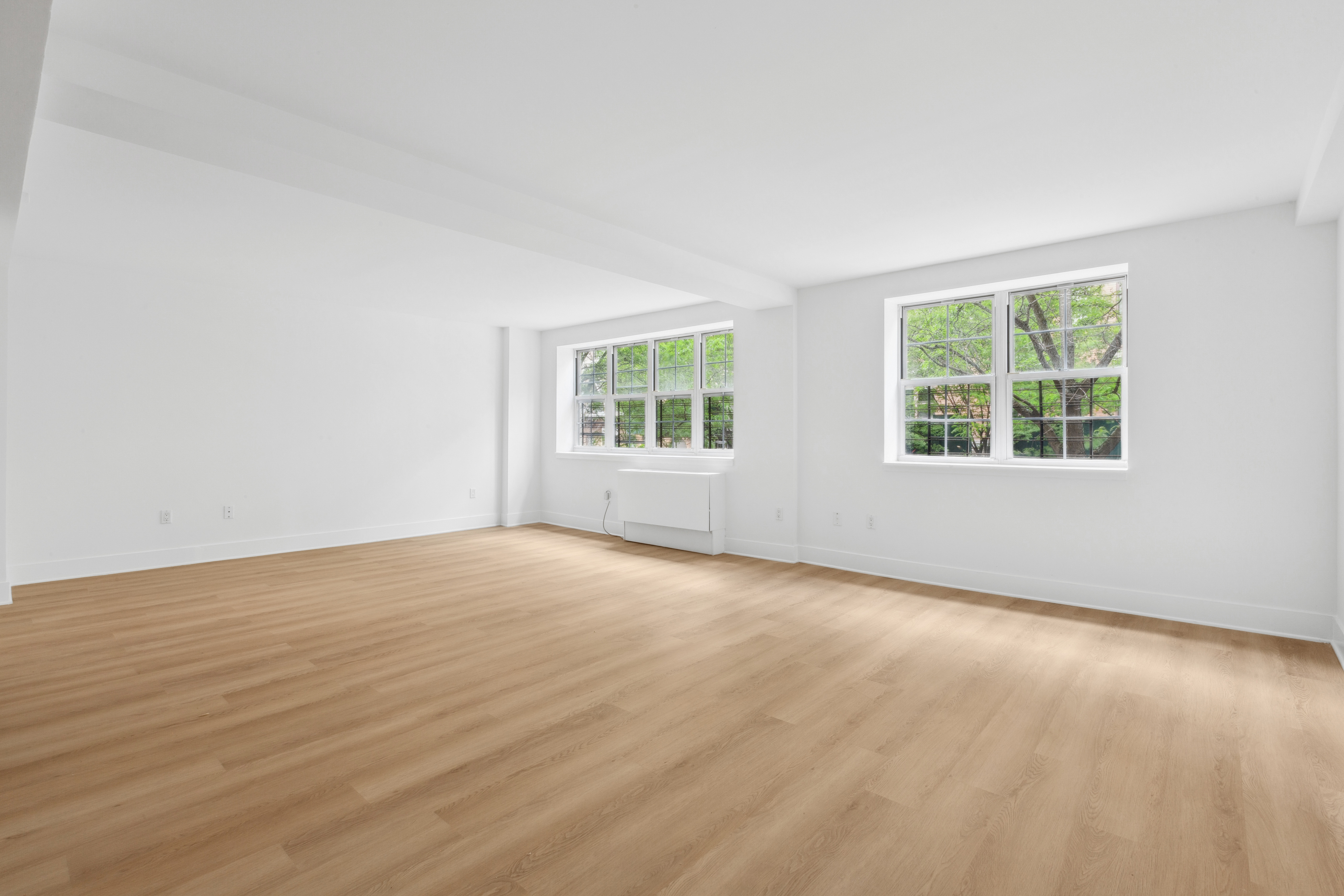 266 West 115th Street, Unit 2B Manhattan, NY 10026 - Photo 2 of 11 an empty room with wooden floor and windows