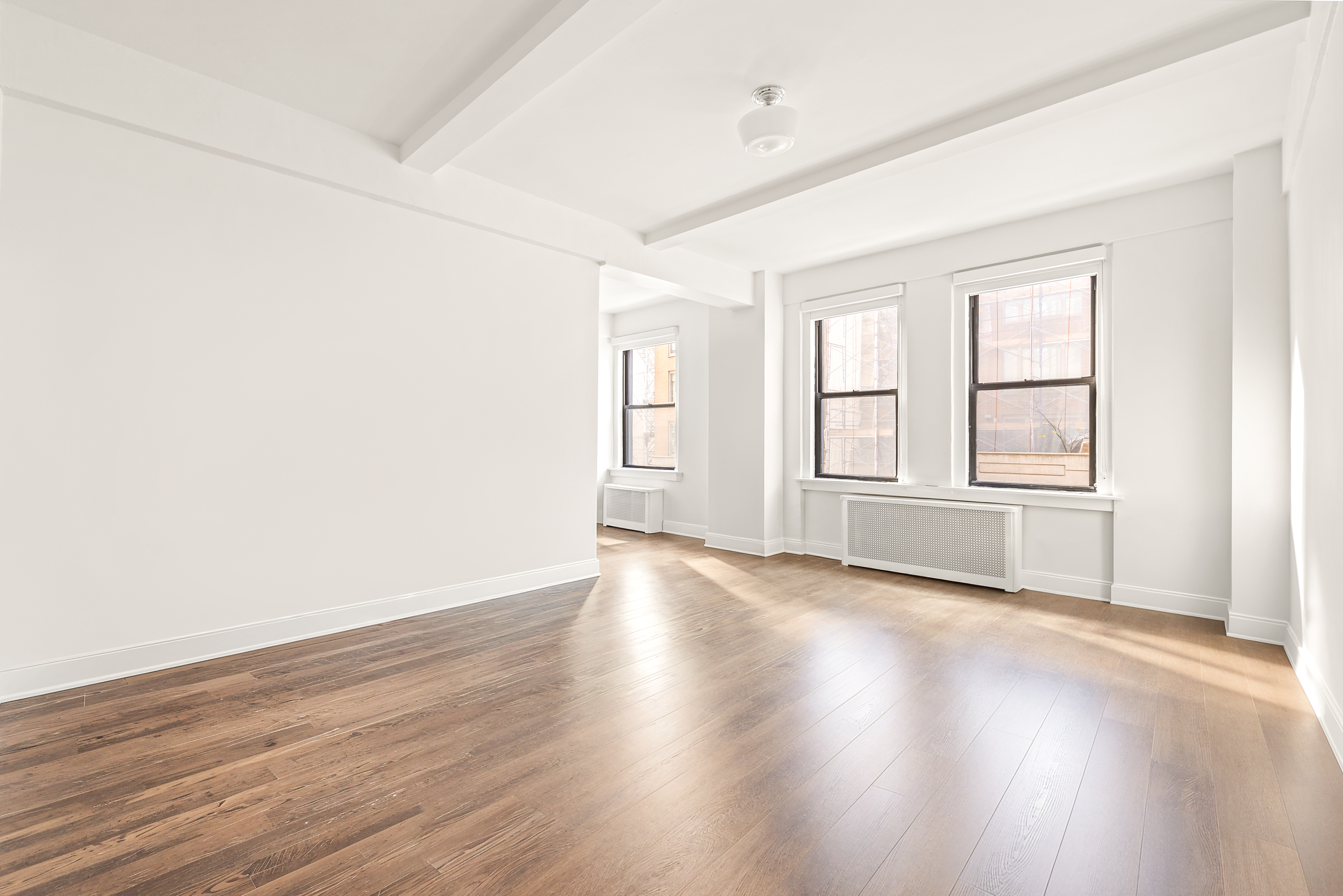 12 East 86th Street, Unit 402 Manhattan, NY 10028 - Photo 2 of 10 an empty room with wooden floor and windows