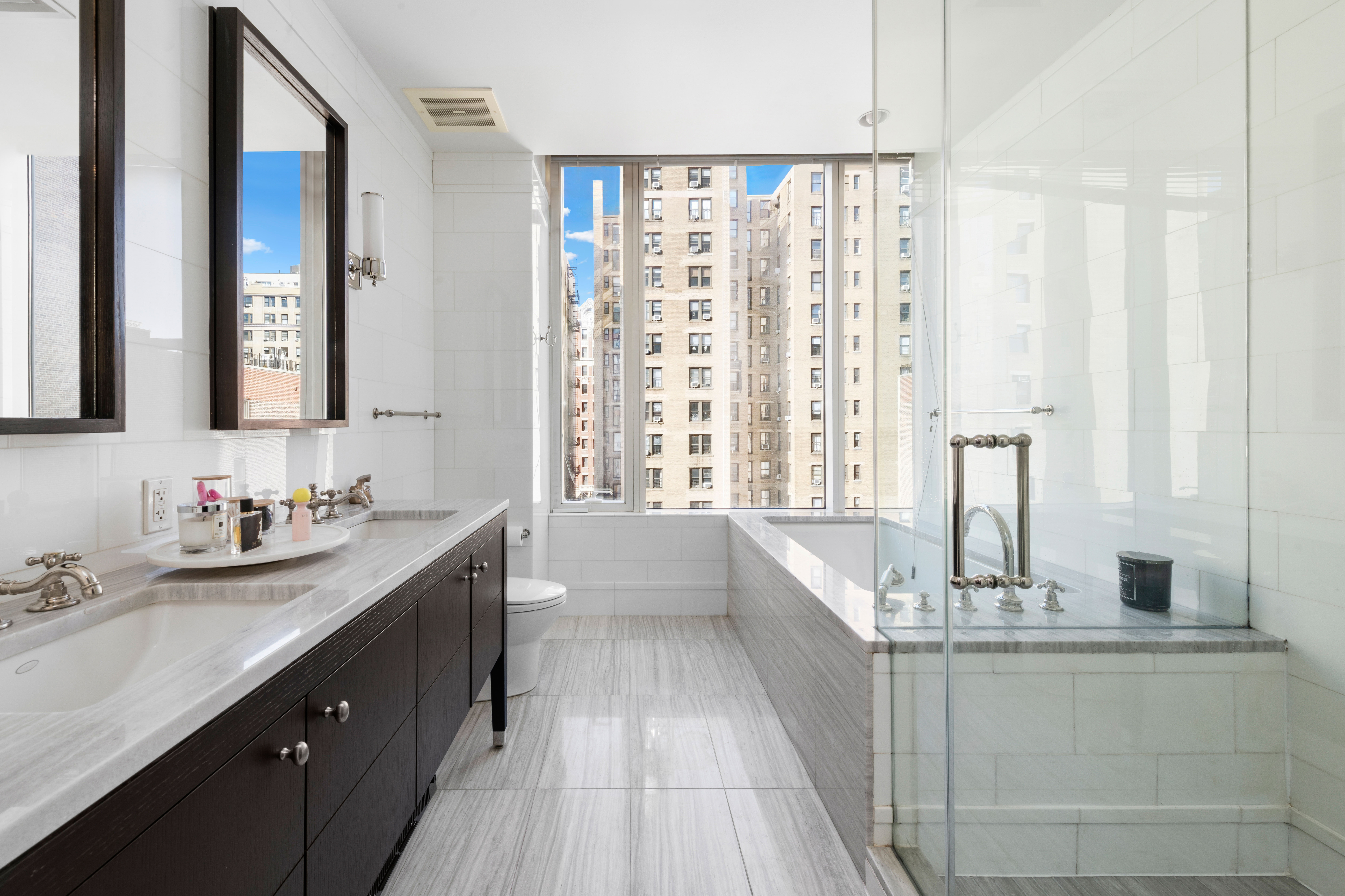 245 West 99th Street, Unit 8A Manhattan, NY 10025 - Photo 7 of 12 a bathroom with a double vanity sink a mirror and a bathtub