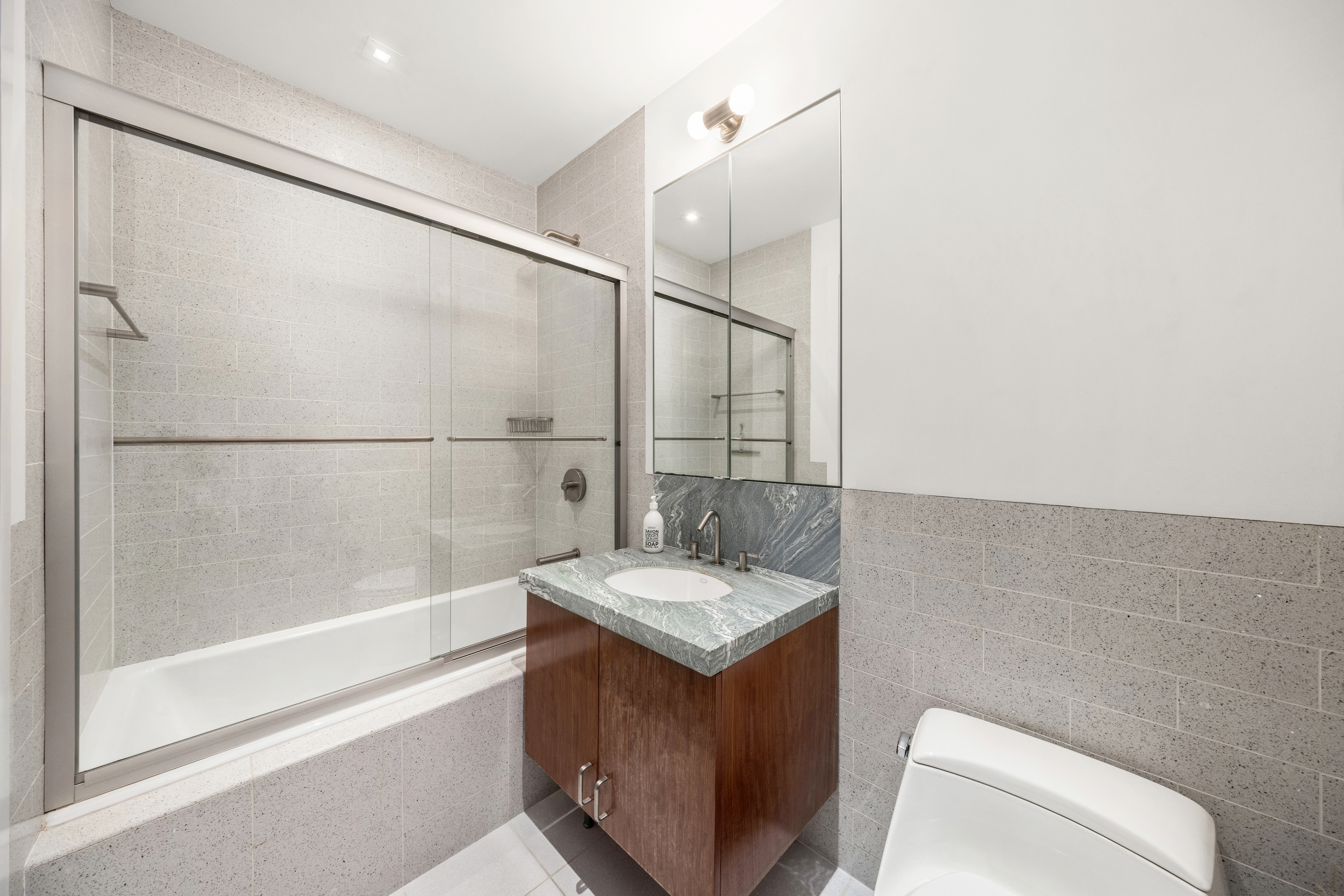 138 Reade Street, Unit 5 Manhattan, NY 10013 - Photo 17 of 23 a bathroom with a granite countertop sink mirror vanity and bathtub