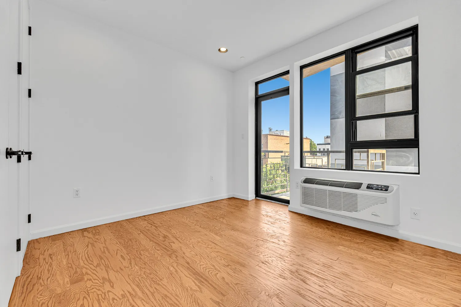 a view of an empty room with a window and wooden floor