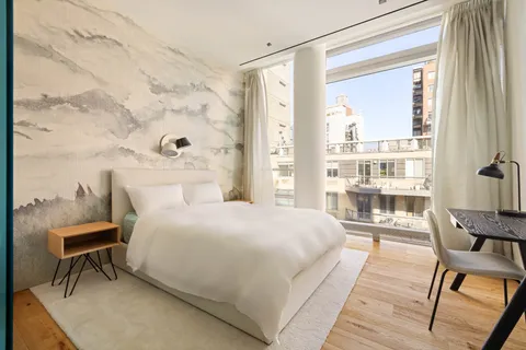 a bedroom with a bed chair and a large window