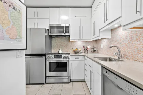 a kitchen with stainless steel appliances granite countertop white cabinets a refrigerator a sink and a stove