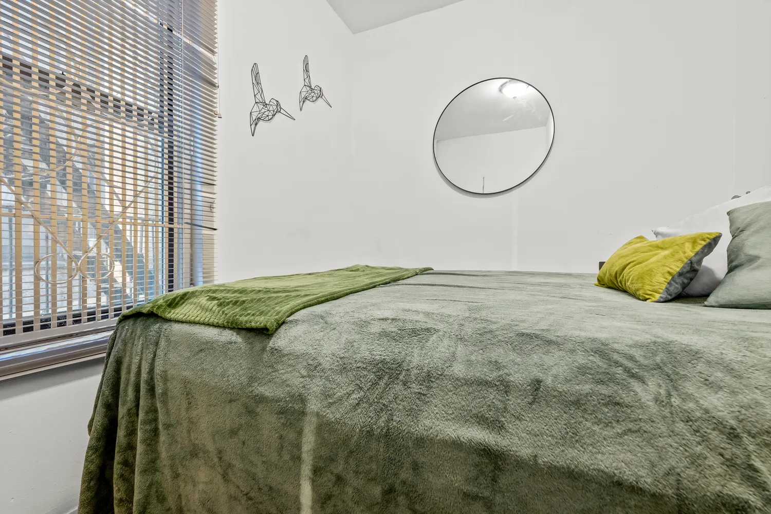 a bed sitting in a bedroom next to a window and a mirror