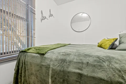 a bed sitting in a bedroom next to a window and a mirror