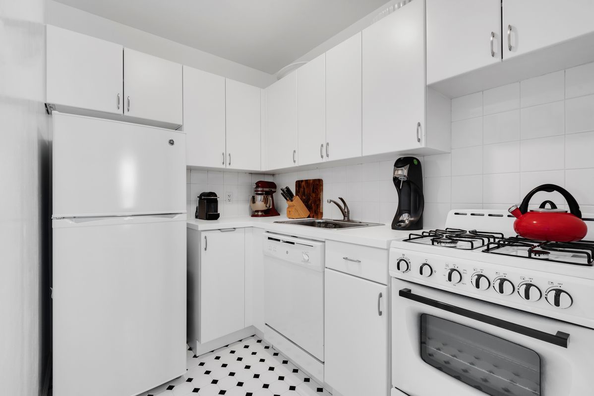 143 Avenue B, Unit 12E Manhattan, NY 10009 - Photo 5 of 8 a kitchen with appliances a refrigerator a stove and cabinets