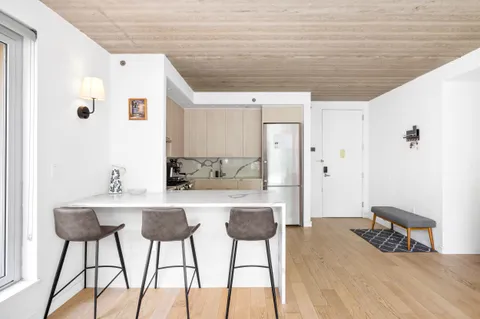 a kitchen with stainless steel appliances a white refrigerator a stove a dining table and chairs with wooden floor