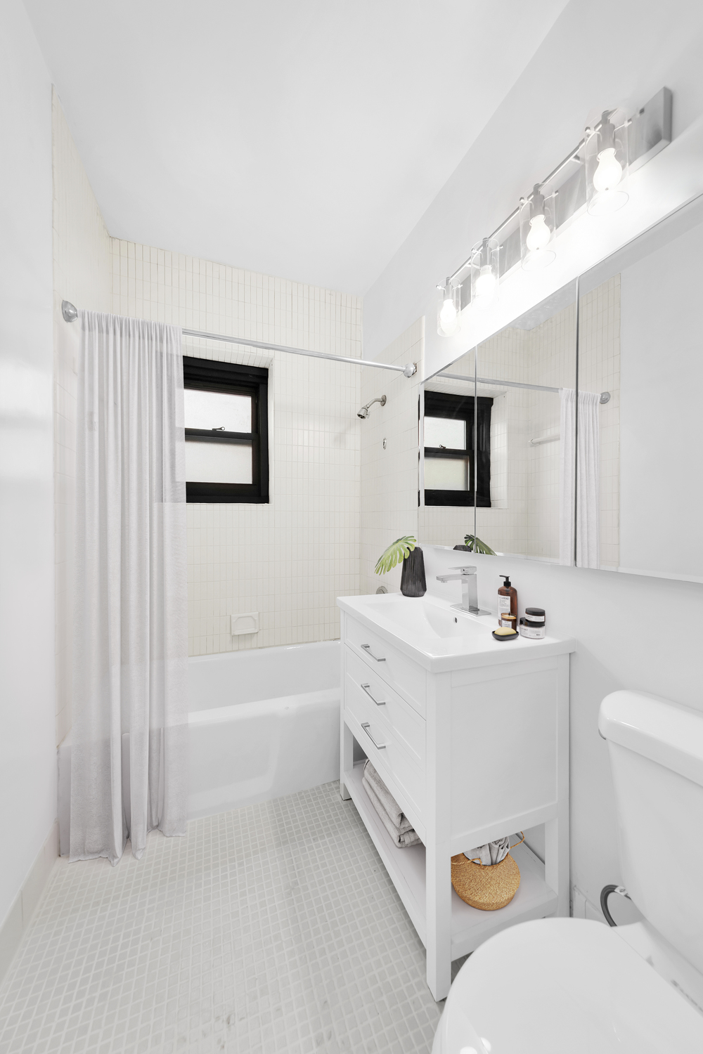58 West 58th Street, Unit 21C Manhattan, NY 10019 - Photo 10 of 12 a bathroom with a sink a toilet a mirror and shower