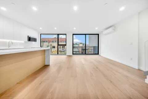 a large kitchen with stainless steel appliances a large counter top a wooden floors and a large window