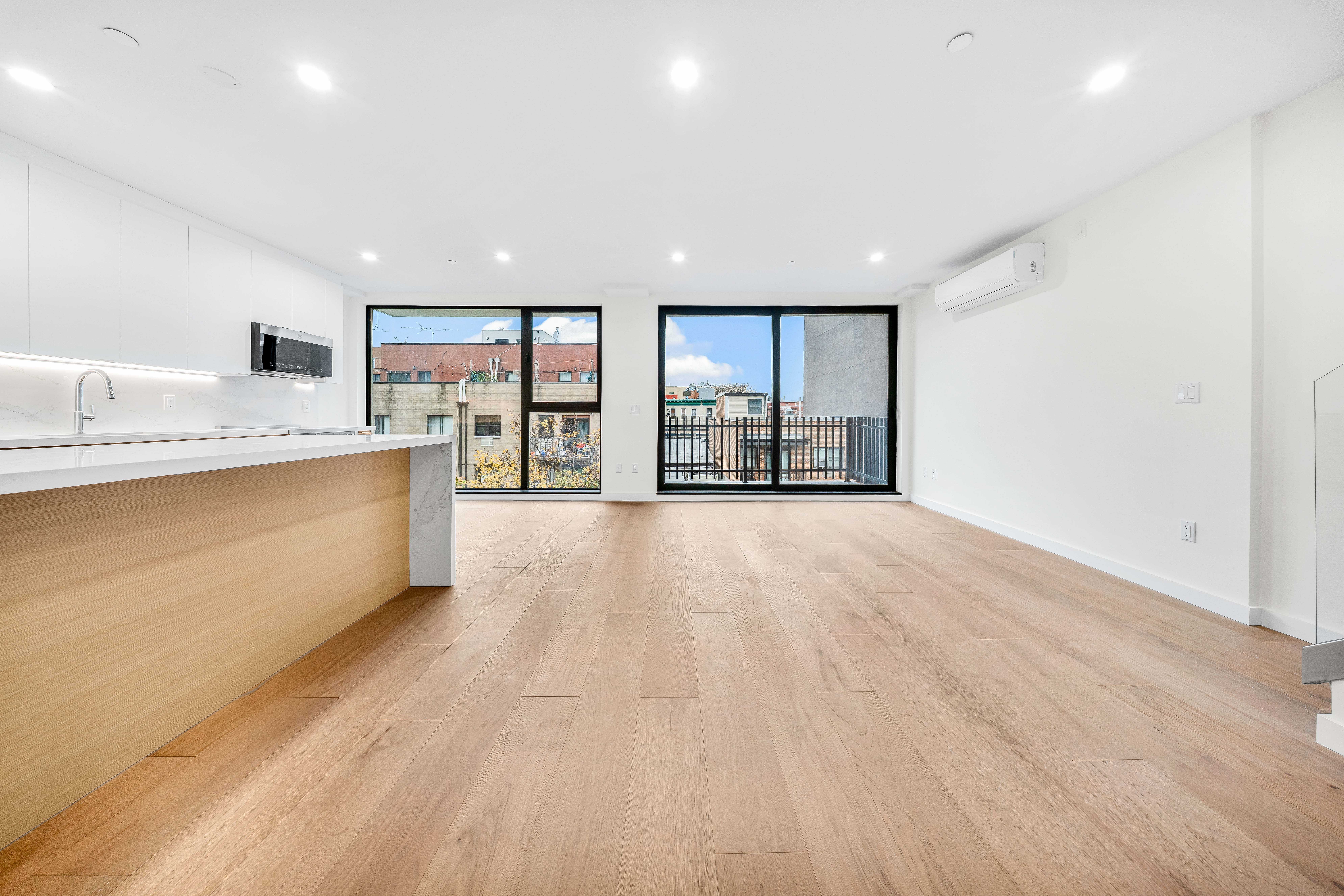 30-24 32nd Street, Unit 4A Queens, NY 11102 - Photo 13 of 22 a large kitchen with stainless steel appliances a large counter top a wooden floors and a large window