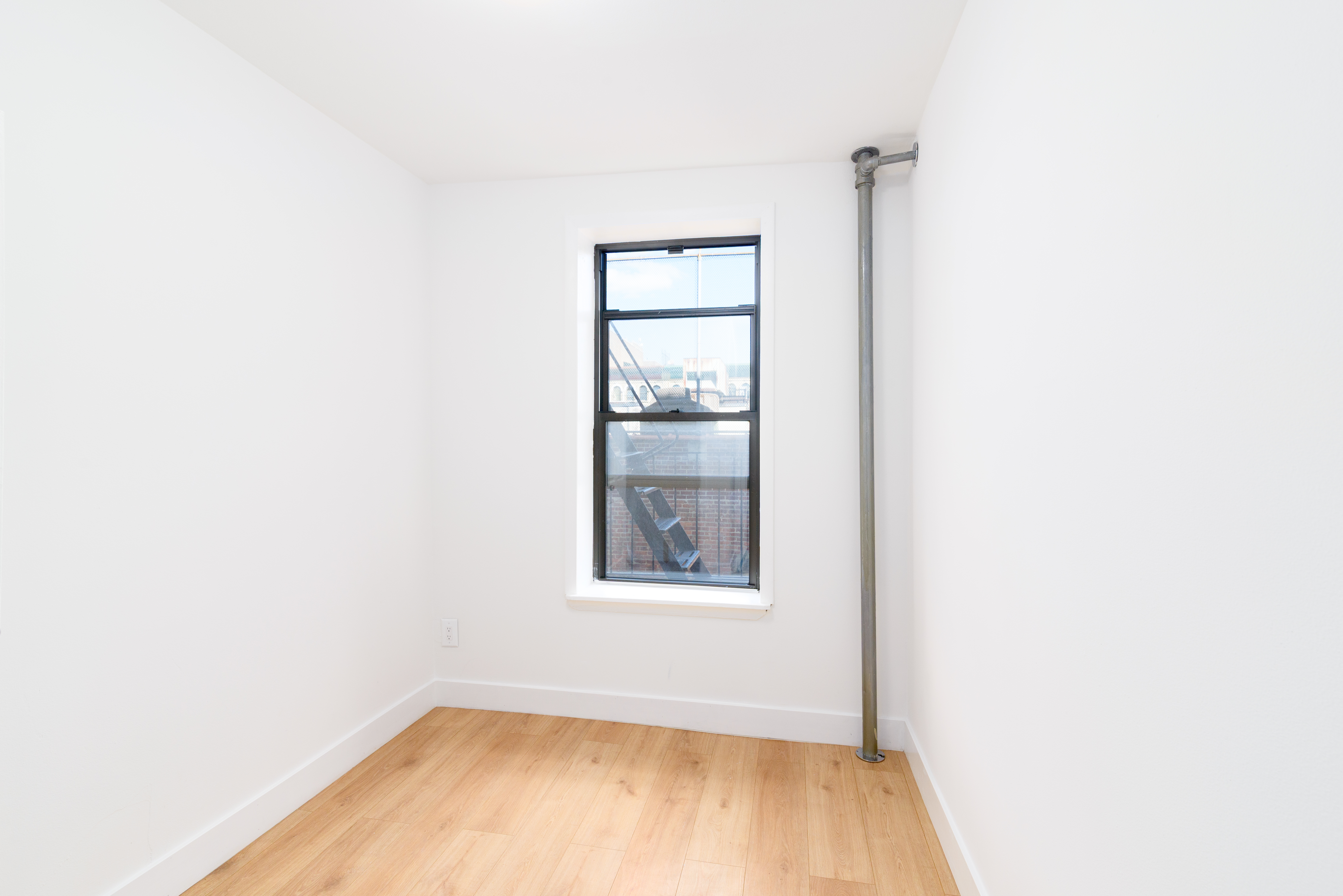 517 West 144th Street, Unit 9 Manhattan, NY 10031 - Photo 8 of 22 a view of an empty room with wooden floor and a window