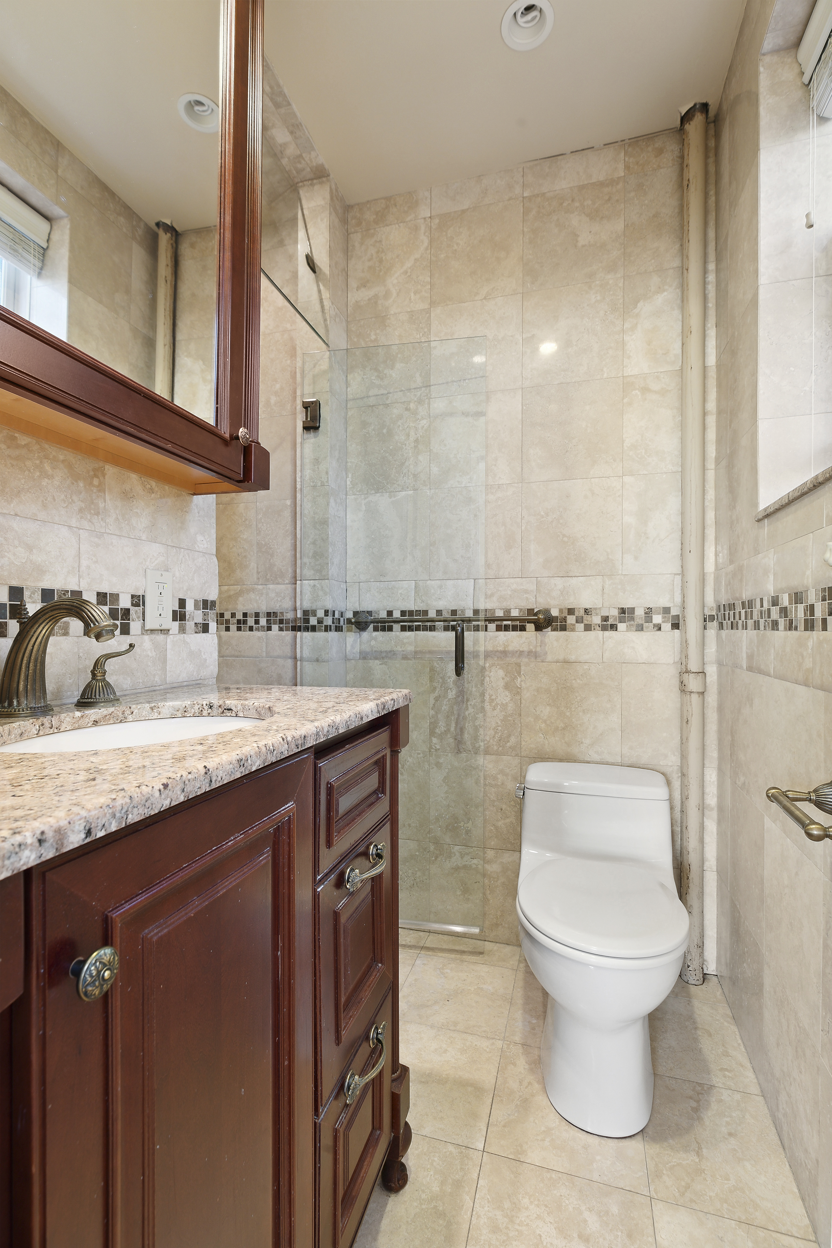 9801 Shore Road, Unit 5A Brooklyn, NY 11209 - Photo 7 of 11 a bathroom with a granite countertop sink a toilet and a mirror