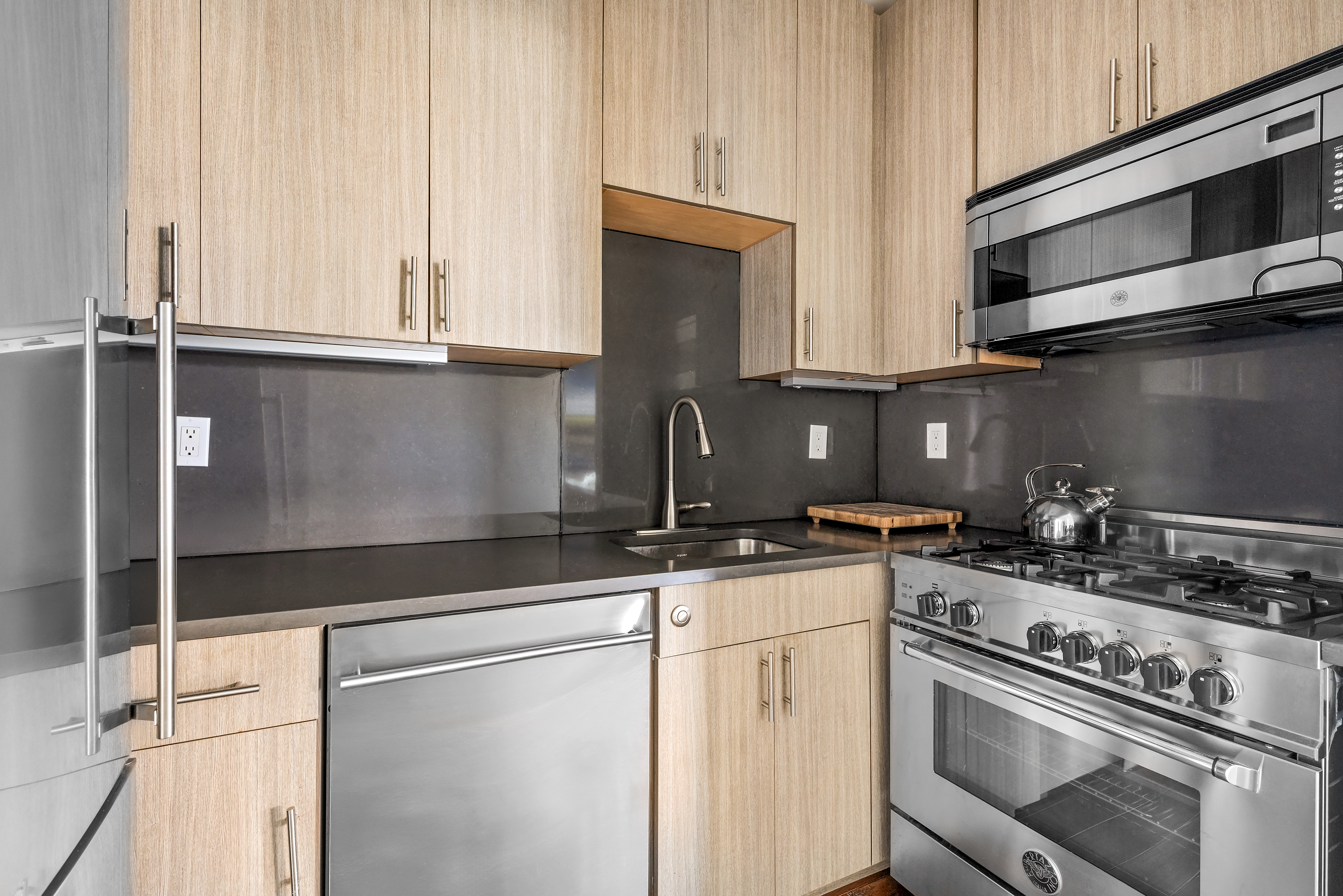 264 Water Street, Unit 6C Manhattan, NY 10038 - Photo 6 of 9 a kitchen with granite countertop a stove sink and cabinets