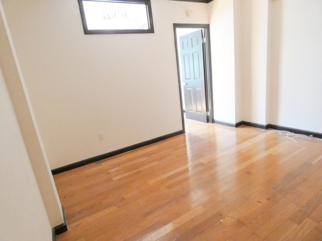 1773 1st Avenue, Unit 9 Manhattan, NY 10128 - Photo 4 of 5 an empty room with wooden floor and windows
