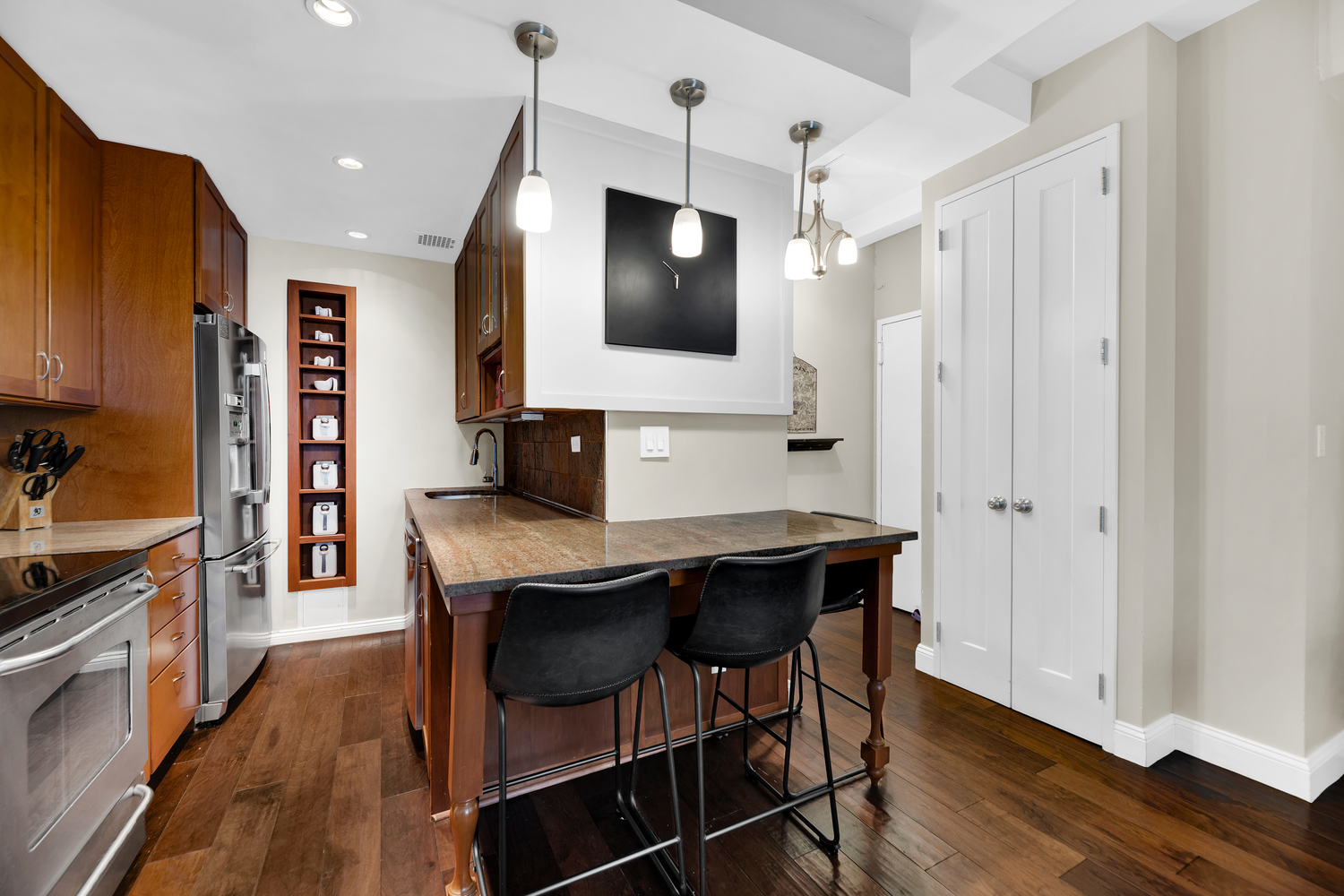 23 East 10th Street, Unit 321 Manhattan, NY 10003 - Photo 2 of 10 a dining room with stainless steel appliances kitchen island granite countertop a table chairs and a refrigerator