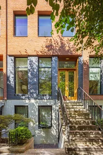 front view of a brick house with a large tree