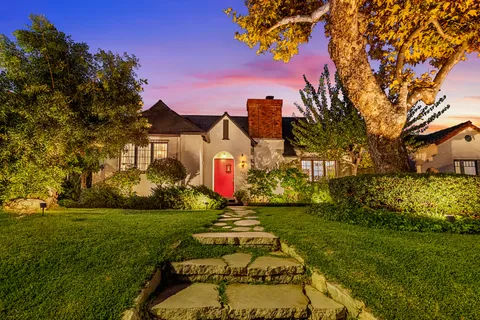a front view of a house with a yard and potted plants