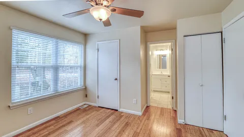 a view of an empty room with wooden floor and a window
