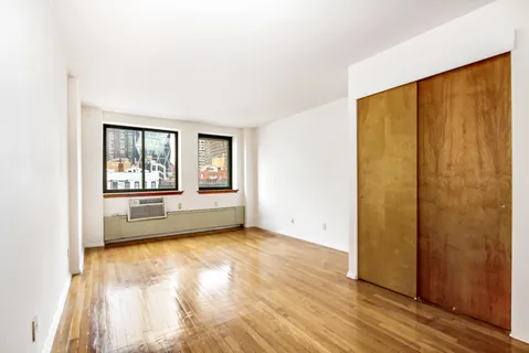a view of an empty room with a window and wooden floor