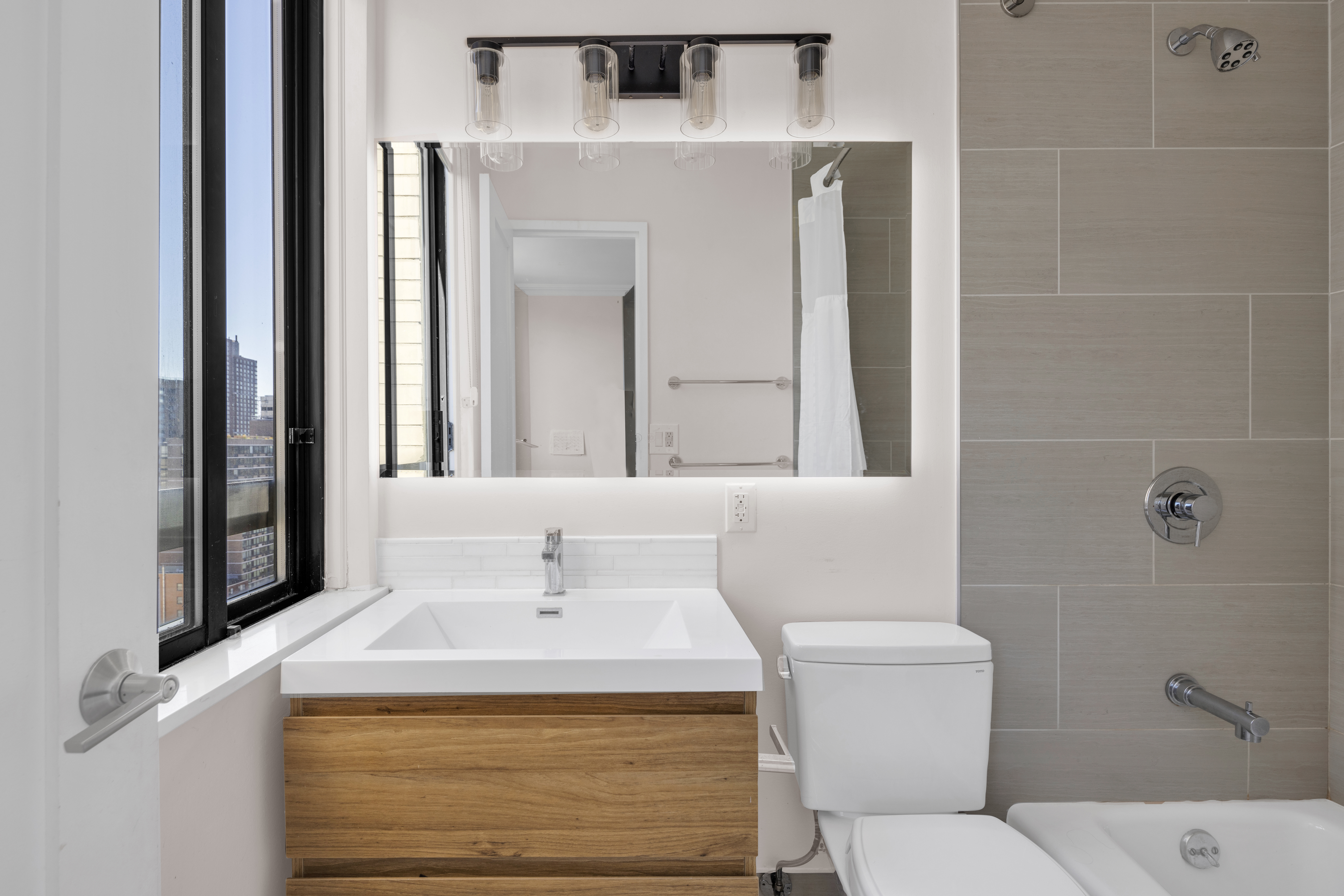 171 East 84th Street, Unit 22C Manhattan, NY 10028 - Photo 9 of 17 a bathroom with a sink a toilet and mirror