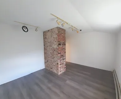a view of an empty room with wooden floor and windows