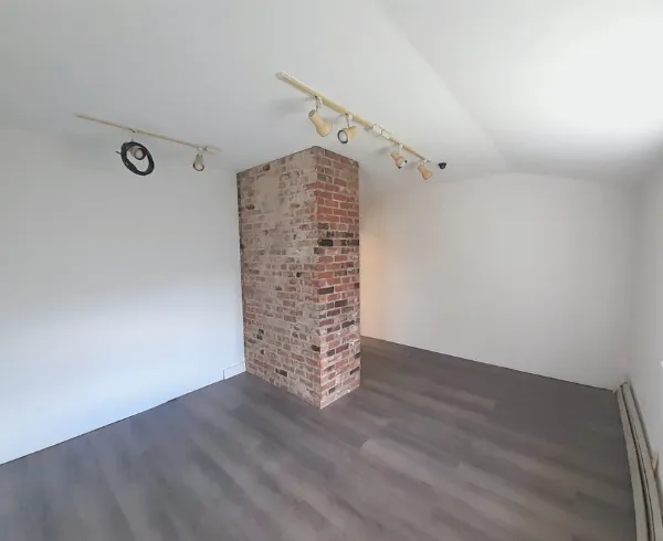 a view of an empty room with wooden floor and windows