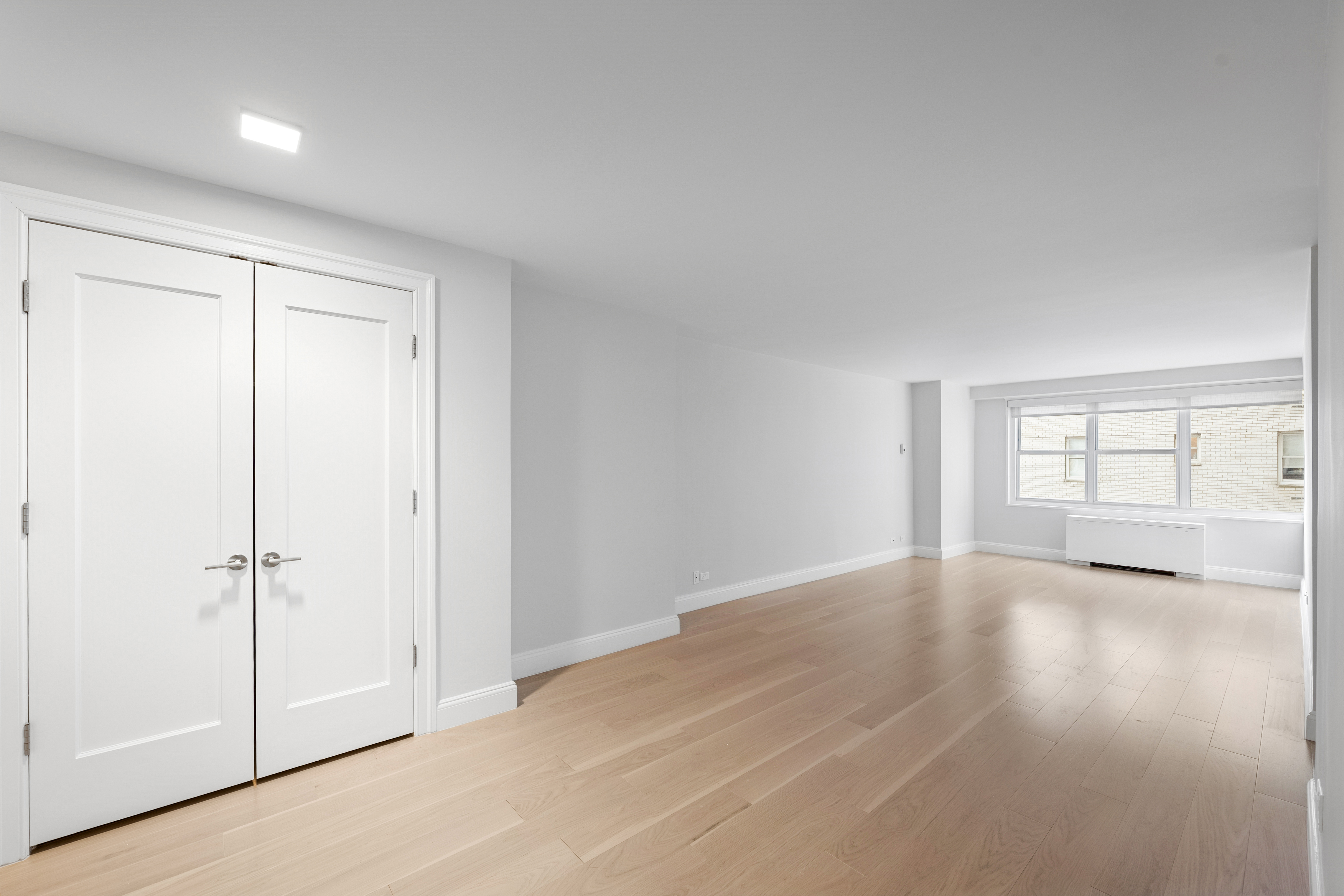 155 West 68th Street, Unit 815 Manhattan, NY 10023 - Photo 4 of 14 an empty room with wooden floor closet and windows