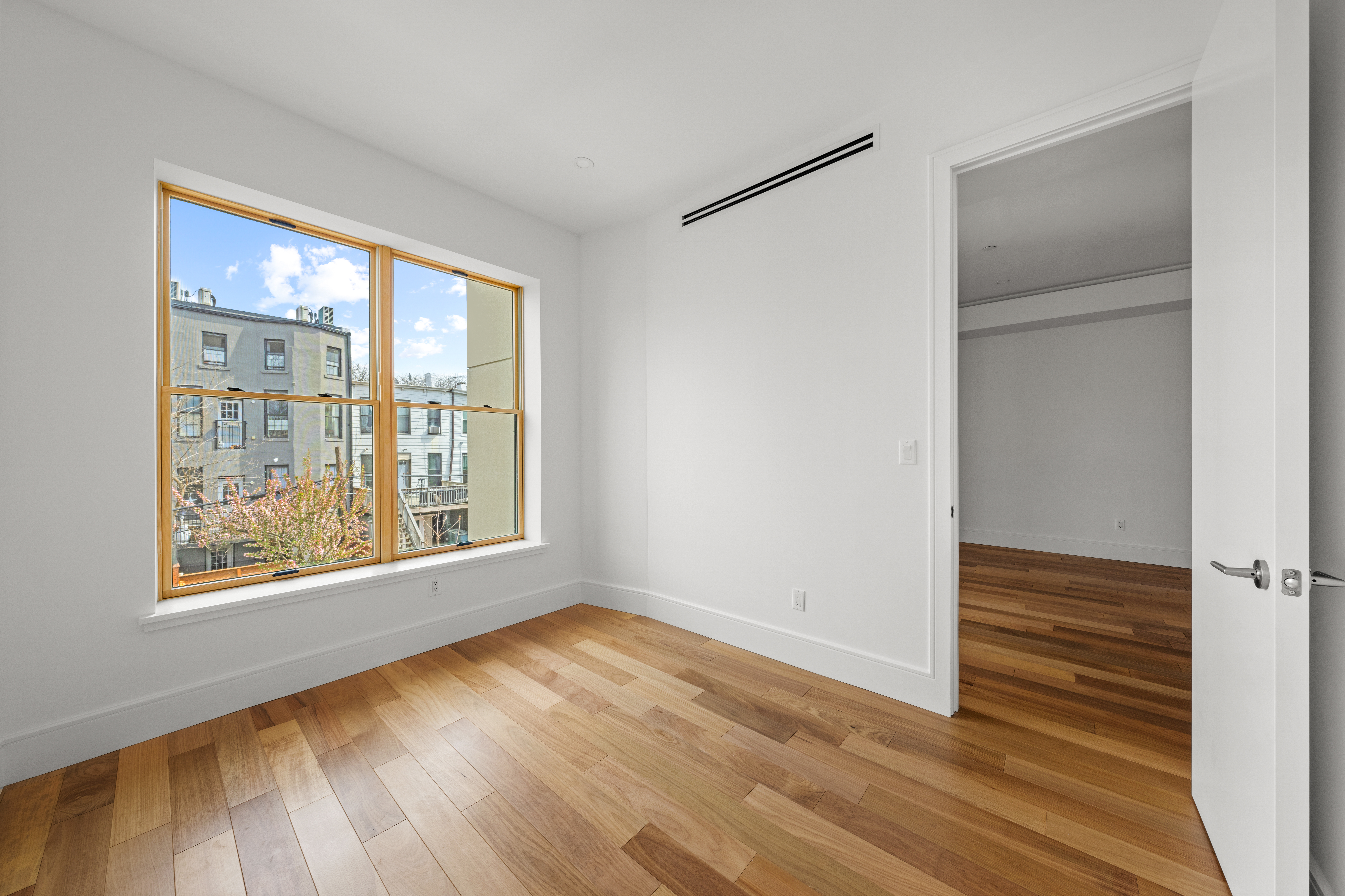 82 Cooper Street, Unit 2B Brooklyn, NY 11207 - Photo 8 of 17 a view of an empty room with wooden floor and a window