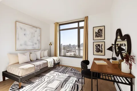 a bedroom with a bed wooden floor and windows