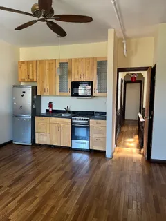 a kitchen with stainless steel appliances a refrigerator a sink dishwasher a stove and white cabinets with wooden floor