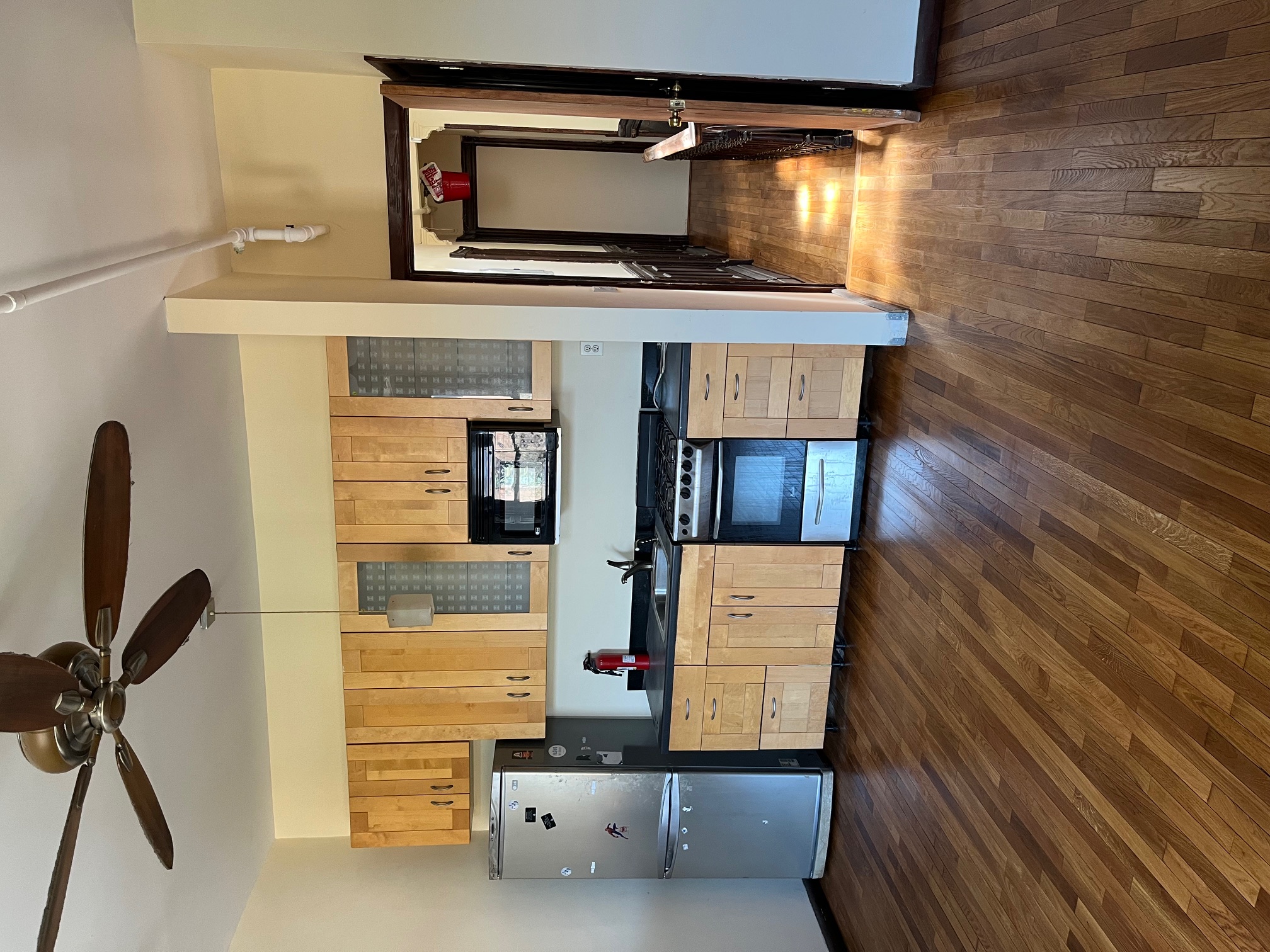 106 West 131st Street Manhattan, NY 10027 - Photo 7 of 16 a kitchen with stainless steel appliances a refrigerator a sink dishwasher a stove and white cabinets with wooden floor