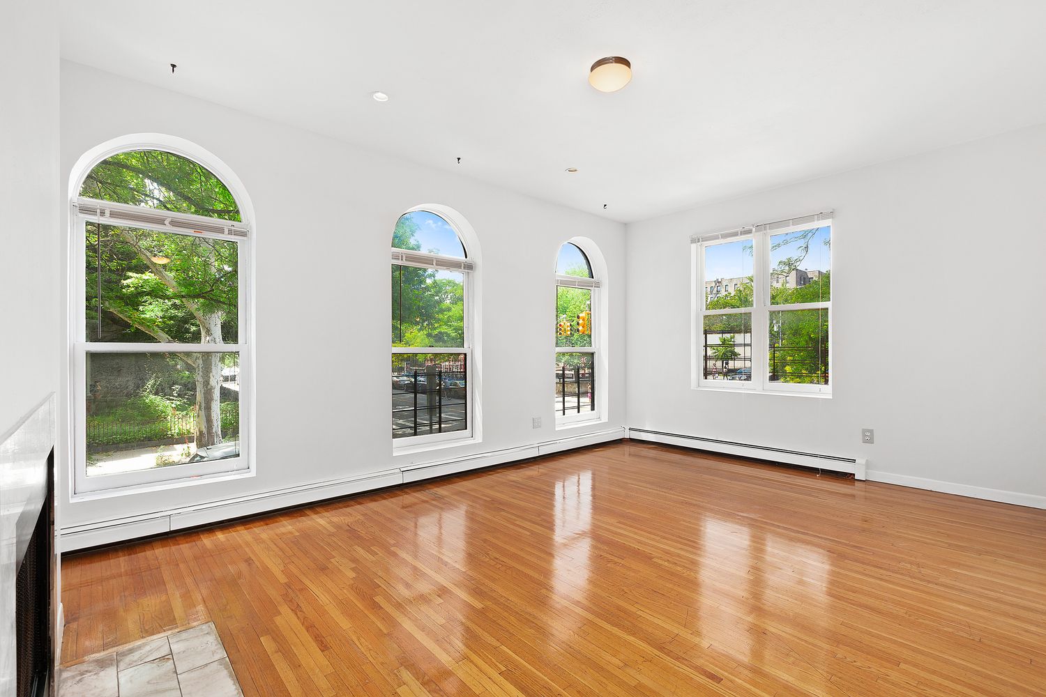 a view of an empty room with wooden floor and windows
