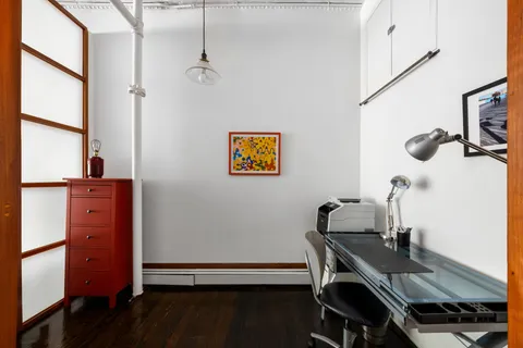 a view of a workspace with furniture and a window